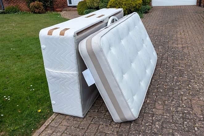 two workers taking mattress to be recycled